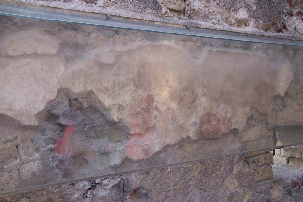 IV.17, Herculaneum, September 2019.
Looking towards south wall with remains of the painted Priapus figure in centre, behind the sales counter.
A second painted figure is also still visible towards the right of the wall. Photo courtesy of Klaus Heese.